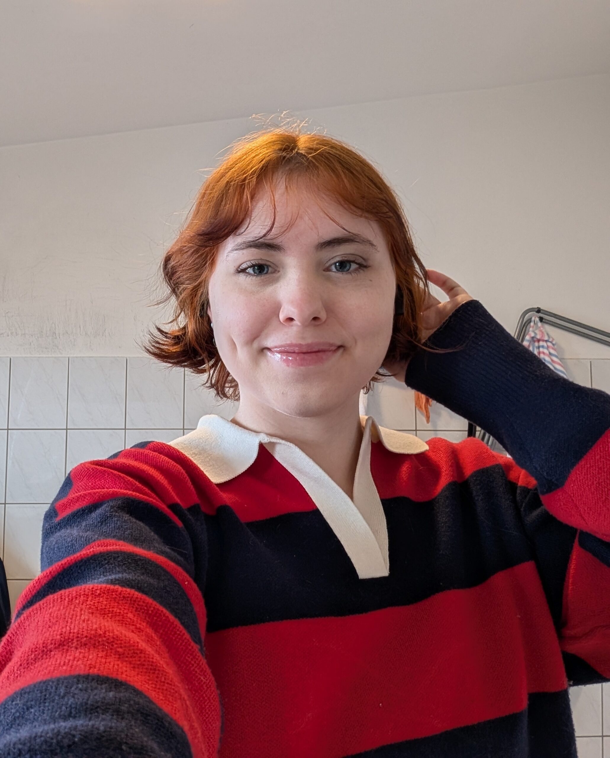Person smiling in striped sweater indoors.